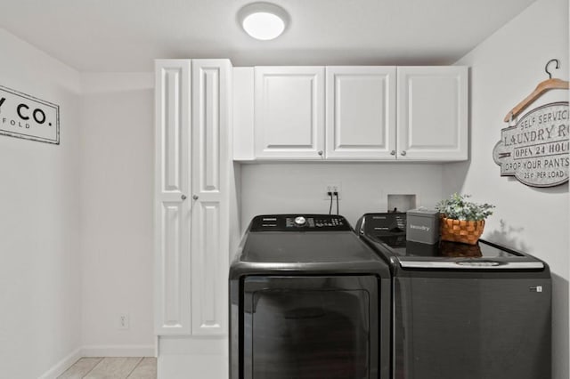 clothes washing area with washer and clothes dryer, light tile patterned floors, and cabinets