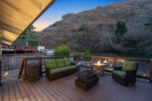 deck at dusk featuring a mountain view and an outdoor living space with a fire pit