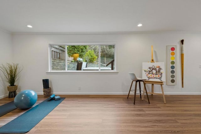 workout area featuring wood-type flooring and ornamental molding