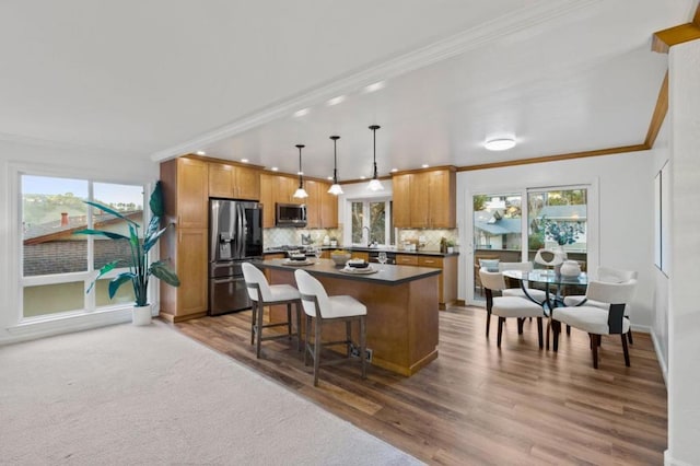 kitchen with stainless steel appliances, crown molding, a kitchen island, and decorative light fixtures