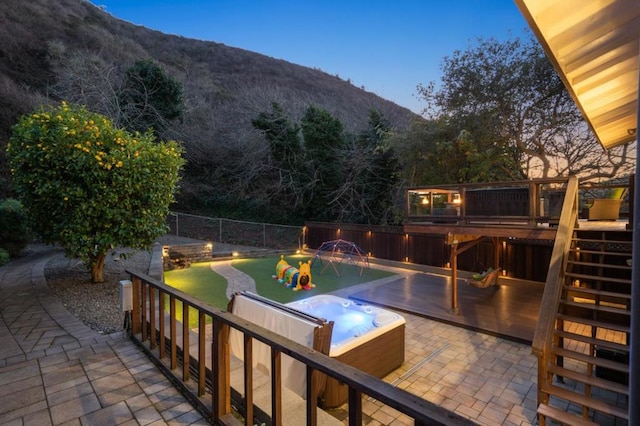 pool at dusk featuring a mountain view and a hot tub