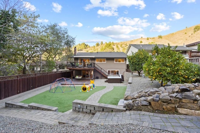 rear view of house featuring a yard, a deck with mountain view, and a patio