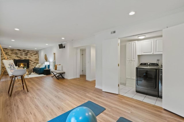 workout room featuring a fireplace, independent washer and dryer, and light hardwood / wood-style floors