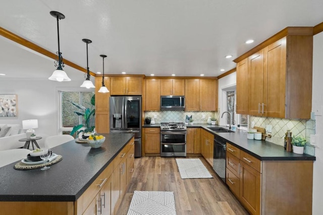 kitchen featuring appliances with stainless steel finishes, decorative light fixtures, light hardwood / wood-style floors, sink, and ornamental molding