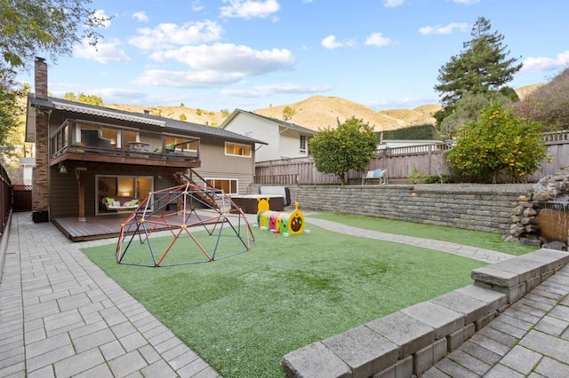 view of yard featuring a balcony, a playground, and a deck with mountain view