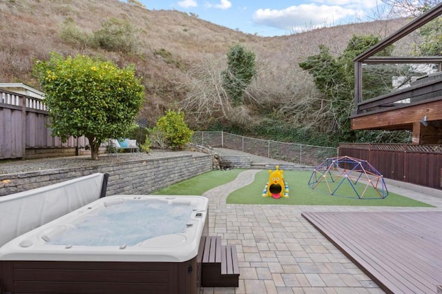 view of patio featuring a hot tub and a deck with mountain view