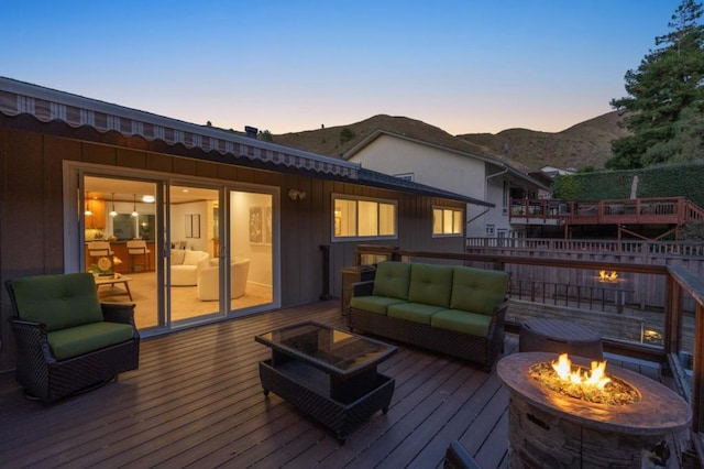 deck at dusk with a mountain view and an outdoor living space with a fire pit