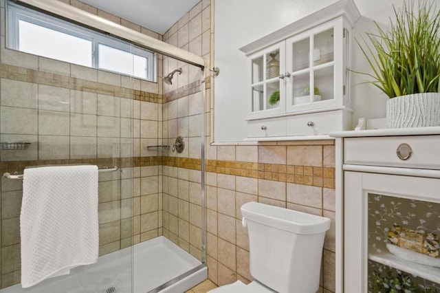 bathroom with toilet, tile walls, and a shower with shower door