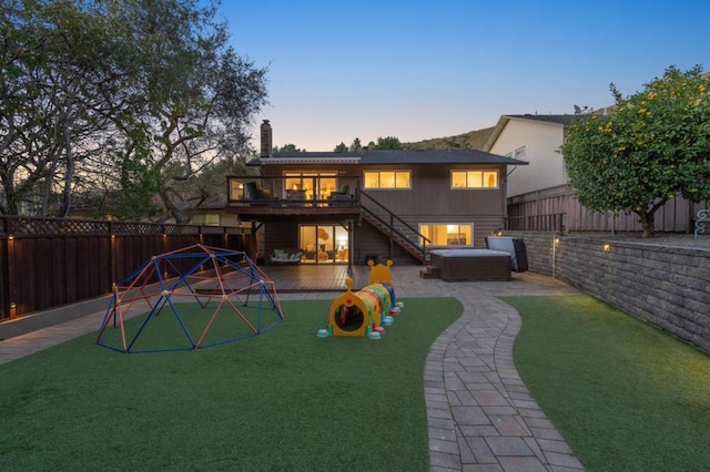 back house at dusk with a lawn and a playground