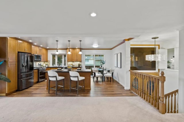 kitchen with appliances with stainless steel finishes, backsplash, decorative light fixtures, a breakfast bar, and a center island