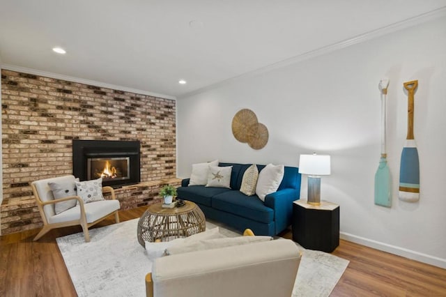 living room with a brick fireplace, hardwood / wood-style floors, and ornamental molding