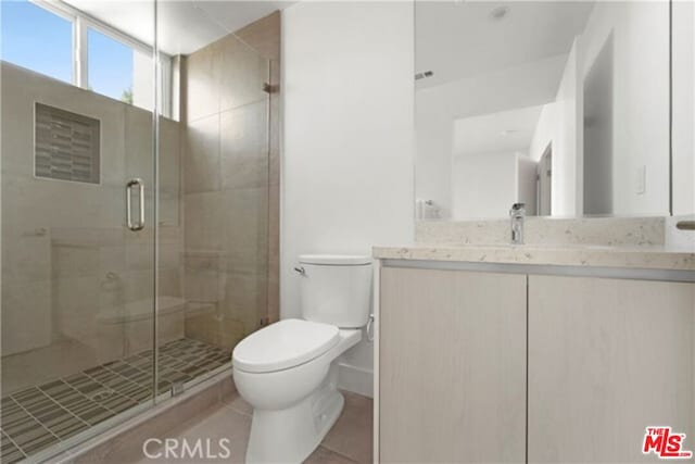 bathroom featuring tile patterned floors, a shower with door, vanity, and toilet