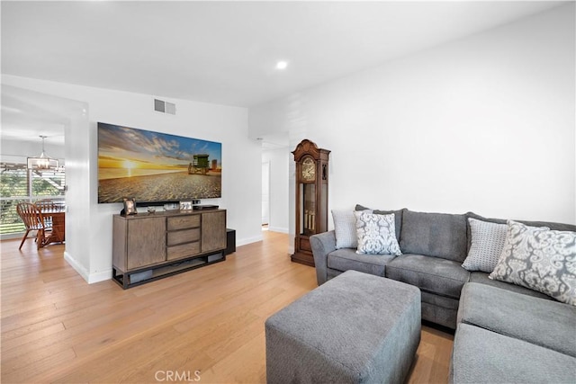 living room featuring lofted ceiling, wood-type flooring, and an inviting chandelier