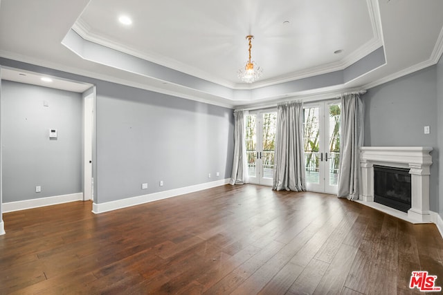 unfurnished living room with a raised ceiling, french doors, dark hardwood / wood-style floors, and a notable chandelier