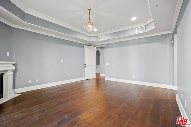 unfurnished living room featuring a tray ceiling, dark hardwood / wood-style floors, ornamental molding, and a chandelier