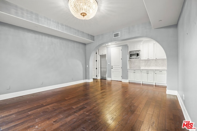 unfurnished living room featuring an inviting chandelier and hardwood / wood-style flooring