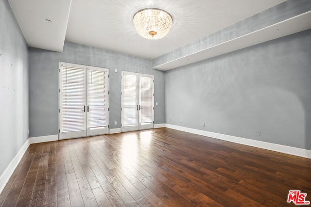 unfurnished room with french doors, dark wood-type flooring, and a chandelier