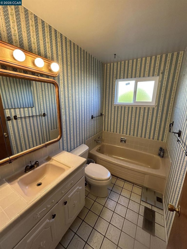 bathroom with toilet, a bath, vanity, and tile patterned flooring