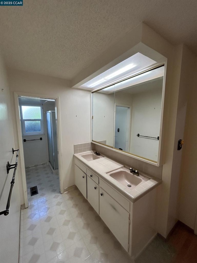 bathroom with walk in shower, vanity, and a textured ceiling