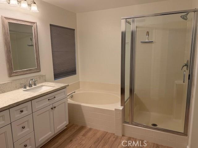 bathroom with vanity, wood-type flooring, and plus walk in shower