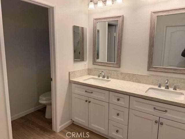 bathroom with toilet, vanity, and hardwood / wood-style floors