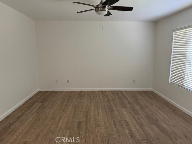 unfurnished room with ceiling fan and dark wood-type flooring