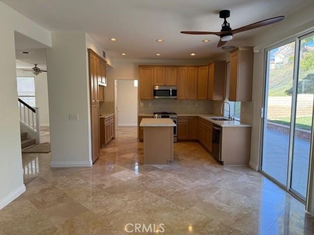 kitchen with ceiling fan, appliances with stainless steel finishes, backsplash, a kitchen island, and sink