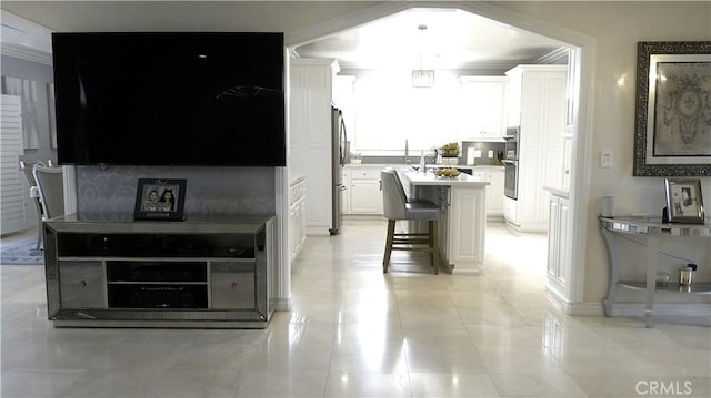 kitchen featuring pendant lighting, a center island with sink, a breakfast bar, white cabinetry, and stainless steel appliances