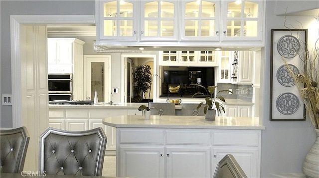 bar with white cabinetry, backsplash, and stainless steel double oven