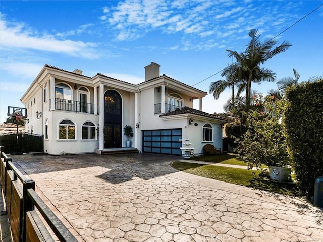 mediterranean / spanish-style home featuring a garage and a balcony