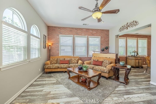 living room with ceiling fan, brick wall, and hardwood / wood-style floors