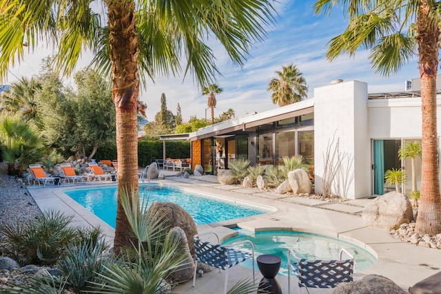 view of swimming pool with pool water feature, a jacuzzi, and a patio area