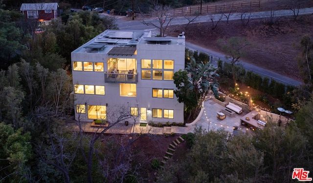 back of house featuring a balcony and solar panels