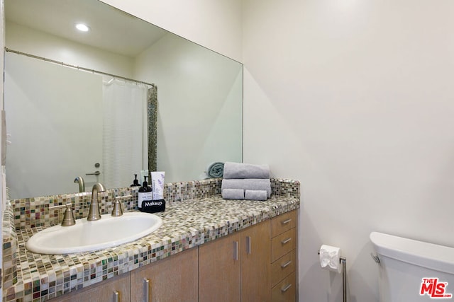 bathroom with toilet, tasteful backsplash, and vanity