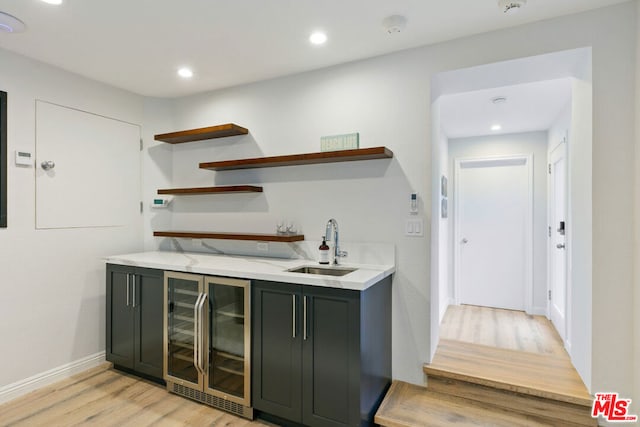 bar with light hardwood / wood-style floors, wine cooler, and sink