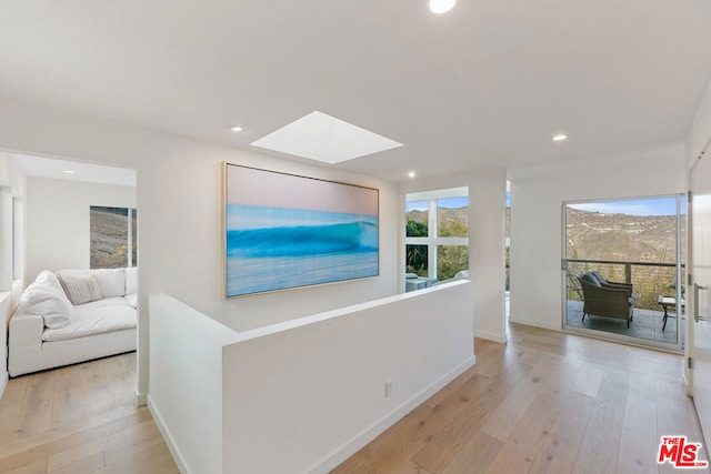 hallway with light hardwood / wood-style flooring and a skylight