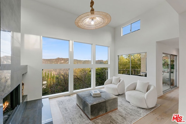 living room with a high ceiling, light wood-type flooring, a premium fireplace, and a mountain view