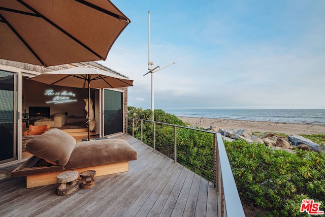 wooden deck featuring a beach view and a water view