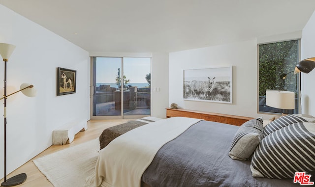 bedroom featuring floor to ceiling windows, access to exterior, and light hardwood / wood-style flooring