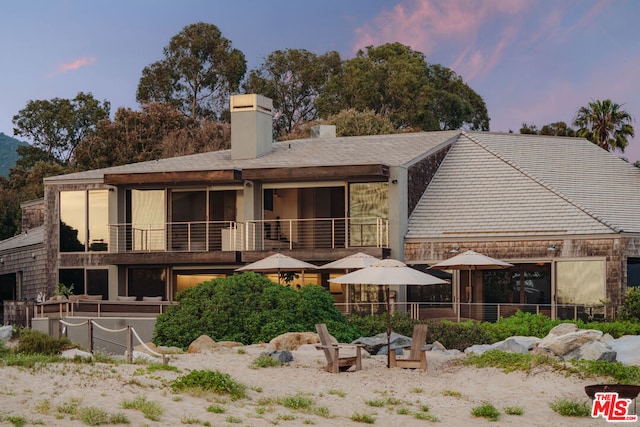 back house at dusk featuring a balcony