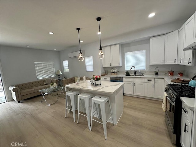 kitchen featuring a center island, white cabinetry, hanging light fixtures, stainless steel range with gas cooktop, and a breakfast bar area