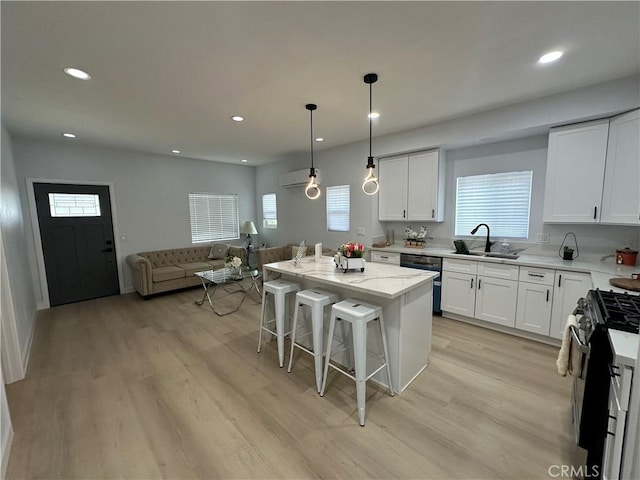 kitchen featuring a kitchen island, a kitchen bar, stainless steel gas range oven, sink, and white cabinetry