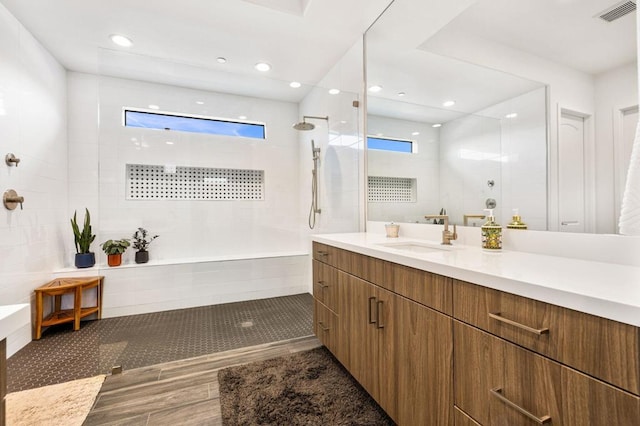 bathroom featuring a wealth of natural light, tiled shower, and vanity