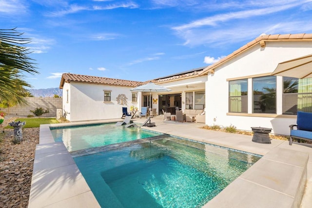 rear view of property with a swimming pool with hot tub and a patio area