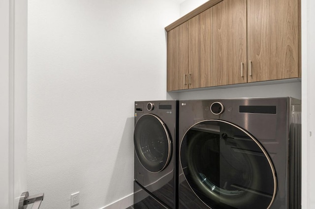 washroom featuring cabinets and washing machine and clothes dryer