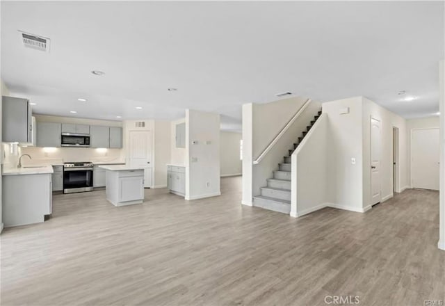 unfurnished living room featuring sink and light wood-type flooring