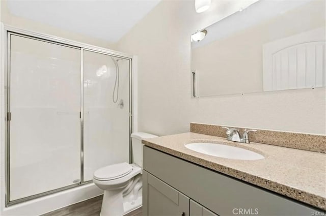 bathroom featuring vanity, wood-type flooring, a shower with door, and toilet