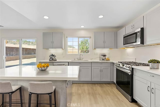 kitchen with a wealth of natural light, appliances with stainless steel finishes, a breakfast bar, and sink