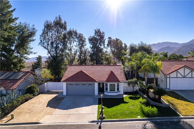 view of front facade featuring a mountain view, a front lawn, and a garage