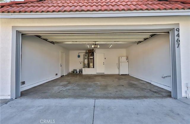 garage featuring water heater, a garage door opener, and white fridge